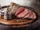 Roast beef on cutting board with saltcellar and pepper mill