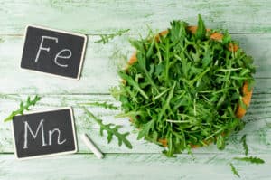 Fresh green arugula in bowl on wooden table