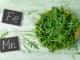 Fresh green arugula in bowl on wooden table