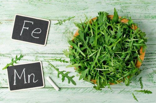 Fresh green arugula in bowl on wooden table